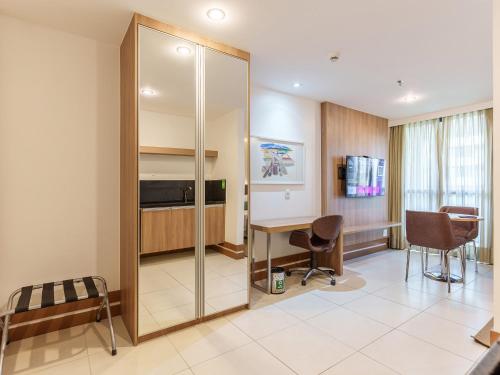 a hotel room with a desk and a sliding glass door at Athos Bulcão Hplus Executive in Brasilia