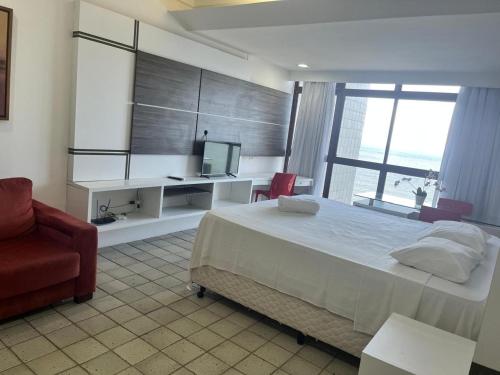 une chambre avec un lit, un bureau et une télévision dans l'établissement Suite Golden Beach Frente Mar, à Récife