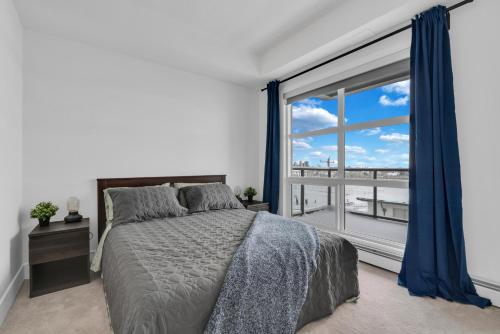 a bedroom with a bed and a large window at Bright Condo with Balcony & Free Parking in Calgary