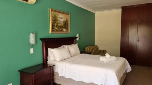 a bedroom with a bed and a green wall at Villa D este in Kimberley