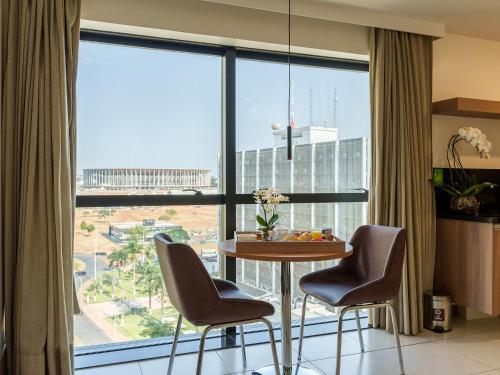 a room with a table and chairs and a large window at Athos Bulcão Hplus Executive in Brasilia