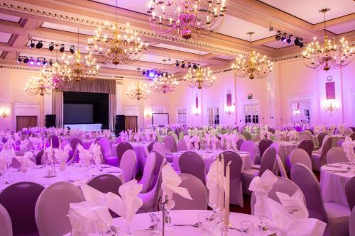 a banquet hall with white tables and chairs and chandeliers at Adelphi Hotel in Liverpool