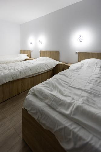 two beds in a room with white sheets at Pensiunea Arieș in Craiova