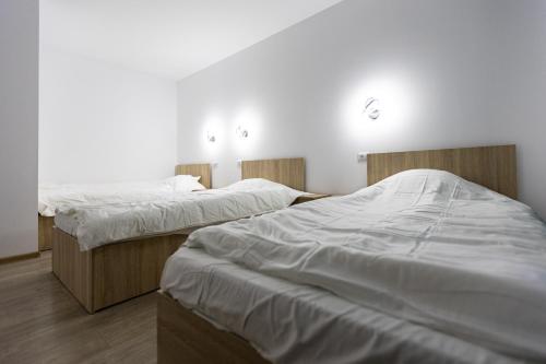 two beds in a room with white sheets at Pensiunea Arieș in Craiova
