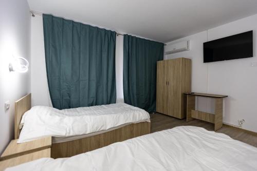 a hotel room with two beds and a flat screen tv at Pensiunea Arieș in Craiova