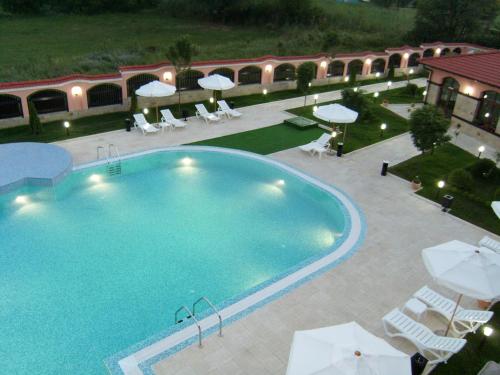 a swimming pool with chairs and umbrellas next to a building at Hotel Domaine Peshtera in Peshtera