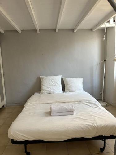 Elle comprend un grand lit avec des draps et des oreillers blancs. dans l'établissement La Madone - Vieux Port, à Marseille