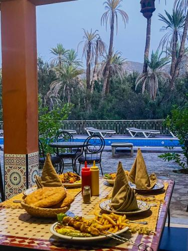 a table with food on it with a view of a pool at tifrit maison d'hôtes-Paradise valley in Imouzzer des Ida Ou Tanane