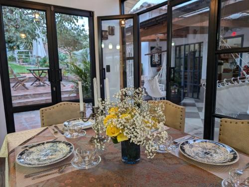 a table with plates and a vase of flowers on it at Quinta Paolita in Tumbabiro