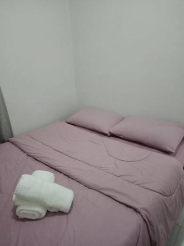 a bed with purple sheets and two folded towels on it at comfy bungalow near ateneo de cebu in Mandaue City