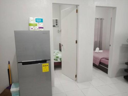 a white room with a refrigerator and a bedroom at comfy bungalow near ateneo de cebu in Mandaue City