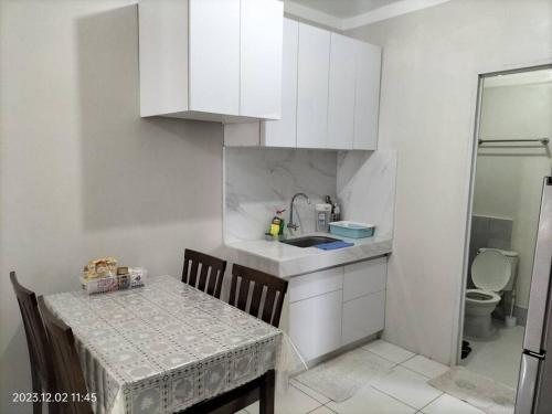 a kitchen with a table and a sink and a toilet at comfy bungalow near ateneo de cebu in Mandaue City