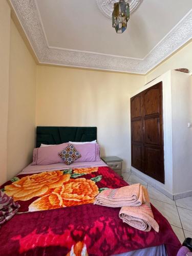 a bedroom with a bed with a red comforter at Dar bennis 2 in Rabat