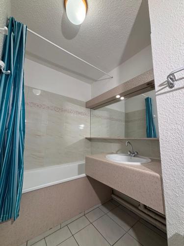 a bathroom with a sink and a mirror and a tub at Résidence Atrey Clés Blanches in La Tania