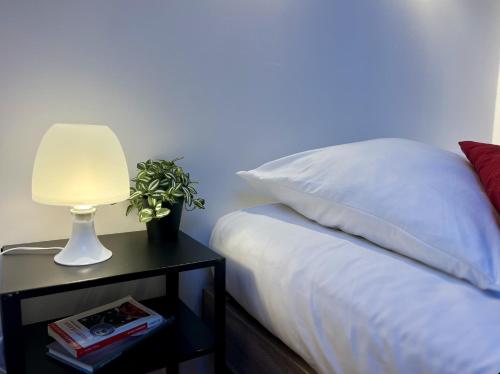 a bed with a lamp on a night stand next to it at La Parenthèse Cozy - À 2 min Basilique & Centre in Saint-Maximin-la-Sainte-Baume