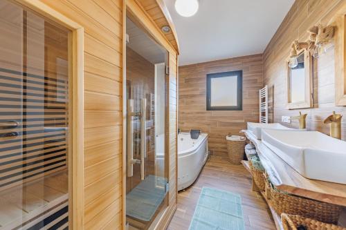 a bathroom with wooden walls and a tub and a sink at Les 4 Saisons des Violonges - Vue montagne in Neussargues en Pinatelle