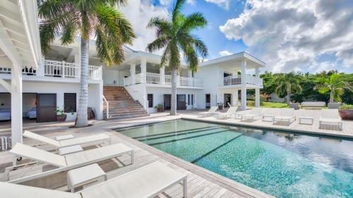 a villa with a swimming pool and palm trees at Stunning 6BR Villa Near Longue Bay Beach in Baie Longue