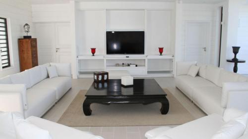 a living room with white furniture and a flat screen tv at Stunning 6BR Villa Near Longue Bay Beach in Baie Longue