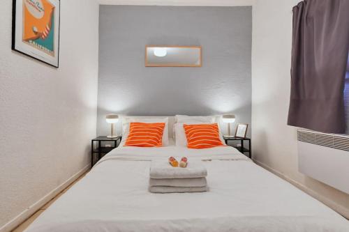 una camera da letto con un grande letto bianco con cuscini arancioni di Le Grand Marseillais Terrasse vu Notre Dame a Marsiglia