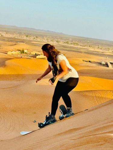 a woman standing on a snowboard in the desert at Brilliant luxury camp in Merzouga