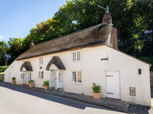 a white cottage with a thatched roof on a street at Amy Cottage in Wareham