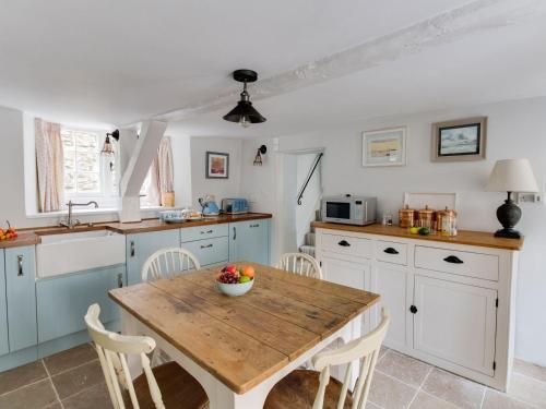 a kitchen with a wooden table and white cabinets at Amy Cottage in Wareham