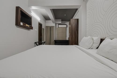 a bedroom with a white bed and a television at Super Townhouse Vidya Vihar in Patna