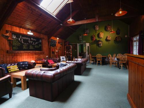 a living room with leather couches and tables and chairs at YHA Borrowdale in Rosthwaite