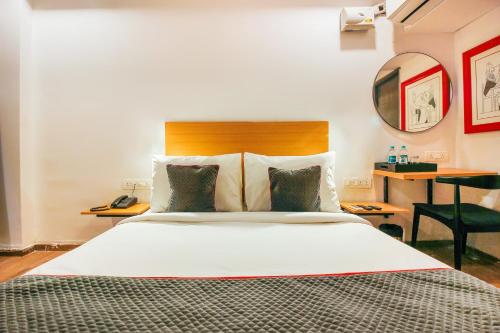 a bedroom with a large white bed and a desk at Super Townhouse RCC Sunrise in Hyderabad