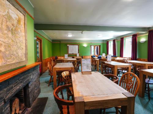 a restaurant with tables and chairs and a fireplace at YHA Borrowdale in Rosthwaite