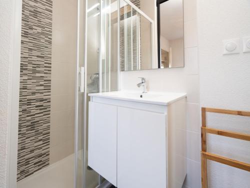 une salle de bain blanche avec un lavabo et un miroir dans l'établissement La Dune 29 - VILLA 4P9, à Valras-Plage