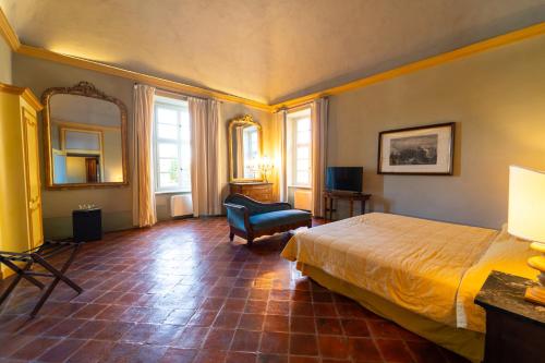 a bedroom with a bed and a chair and a mirror at Foresteria del Castello di San Giorgio Canavese in San Giorgio Canavese