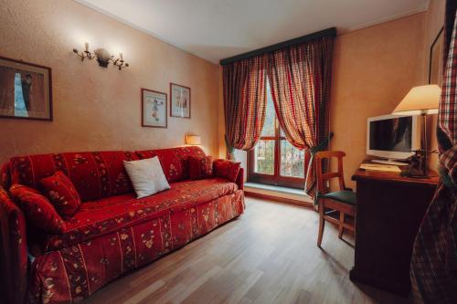 a living room with a red couch and a tv at Villa Novecento Romantic Hotel - Estella Hotel Collection & Experience in Courmayeur