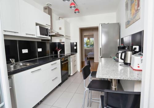 a kitchen with white appliances and black and white cabinets at Charmant appartement avec terrasse dans villa in Strasbourg