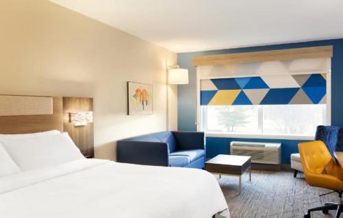 a hotel room with a bed and a chair and a window at Holiday Inn Express & Suites Stevensville - Benton Harbor by IHG in Stevensville