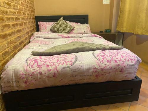 a bed with a pink and white comforter and pillows at Bhaktapur Boutique Hotel and Restaurant in Bhaktapur