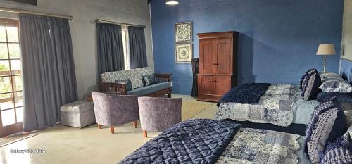 a bedroom with two beds and a crib and a chair at Valley Bushveld Country Lodge in Addo