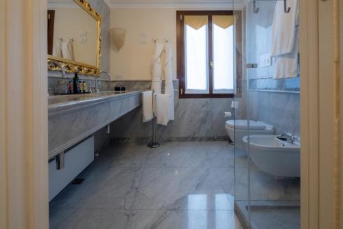 a bathroom with a sink and a toilet and a mirror at Ca' Bonfadini Historic Experience in Venice