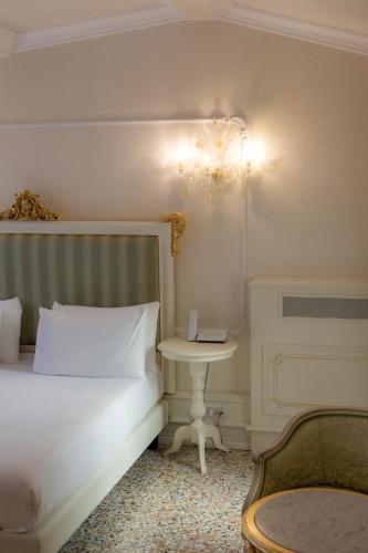 a bedroom with a white bed and a table at Ca' Bonfadini Historic Experience in Venice
