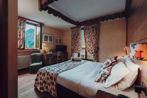 a bedroom with a bed and a desk and windows at Villa Novecento Romantic Hotel - Estella Hotel Collection & Experience in Courmayeur