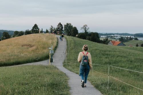 a woman walking down a path in a field at HEIMATEL - Bodensee Residenz Allgäu in Scheidegg
