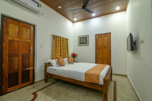 a bedroom with a bed and a wooden door at Thomaskuttys Farmhouse Homestay in Rānī