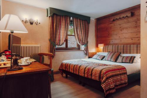 a hotel room with a bed and a desk with a lamp at Villa Novecento Romantic Hotel - Estella Hotel Collection & Experience in Courmayeur