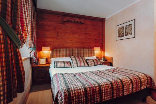 a bedroom with a bed with a wooden headboard at Villa Novecento Romantic Hotel - Estella Hotel Collection & Experience in Courmayeur