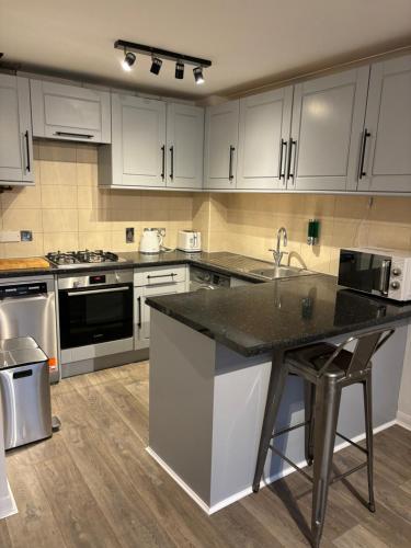 a kitchen with white cabinets and a black counter top at Superb Central Flat, 3 mins to Station and Parking in Staines upon Thames