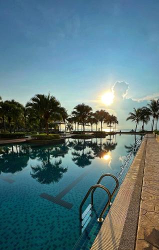 a swimming pool with the sun reflecting in the water at Sea View & Pool View & WiFi & Netflix at Iman Kazoku TimurBay Ville Studio 2BDR in Kuantan