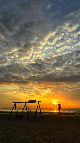 a bench on the beach with the sunset in the background at Sea View & Pool View & WiFi & Netflix at Iman Kazoku TimurBay Ville Studio 2BDR in Kuantan