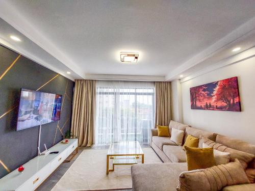 a living room with a couch and a tv at Carolina Homes - Kilimani in Nairobi