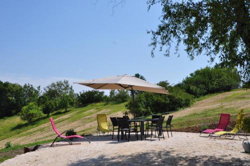 a table with chairs and an umbrella in the sand at Les loups blancs in Moissac