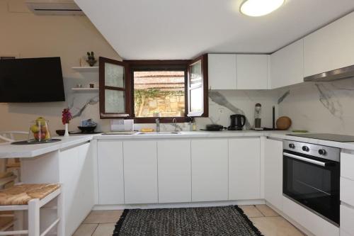 a kitchen with white cabinets and a sink and a window at Efi Cozy Loft with Courtyard in Central Ermoupoli in Ermoupoli
